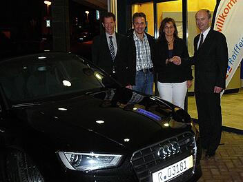 Der Vorstandsvorsitzende der Raiffeisenbank Oberland, Ralph Goller (rechts), gratuliert vor der Hauptgeschäftsstelle Marktleugast (weiter nach links) Nicole und Ralph Schott vor zu ihrem neuen Wagen, einem brillantschwarzen, fünftürigen "Audi A3 Sportback". Mit im Bild (links) der Pressecker Geschäftsstellenleiter Jürgen Goller. Foto: Klaus-Peter Wulf