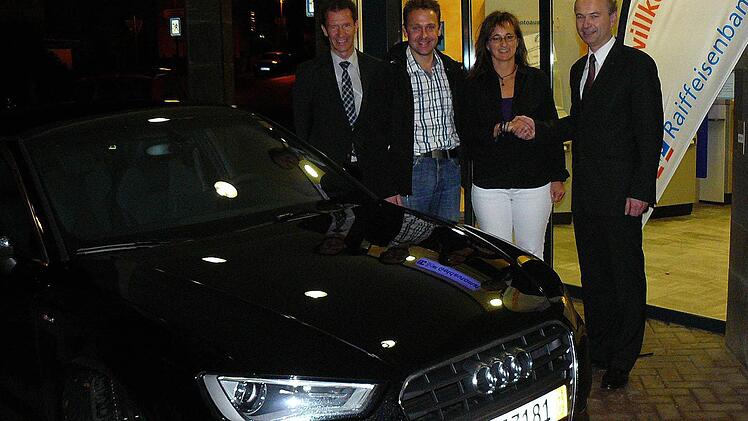Der Vorstandsvorsitzende der Raiffeisenbank Oberland, Ralph Goller (rechts), gratuliert vor der Hauptgeschäftsstelle Marktleugast (weiter nach links) Nicole und Ralph Schott vor zu ihrem neuen Wagen, einem brillantschwarzen, fünftürigen "Audi A3 Sportback". Mit im Bild (links) der Pressecker Geschäftsstellenleiter Jürgen Goller. Foto: Klaus-Peter Wulf