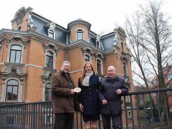 Wer von der Gemeinschaft Stadtbild Coburg einen Zuschuss für die Sanierung seines Hauses erhält, verpflichtet sich, das mit der Bronzeplakette an der Fassade zu dokumentieren. Hans-Heinrich Eidt (links) übergab die Plakette gestern an Danielle St.-Arneault und Detlef Beil. Fotos: Simone Bastian