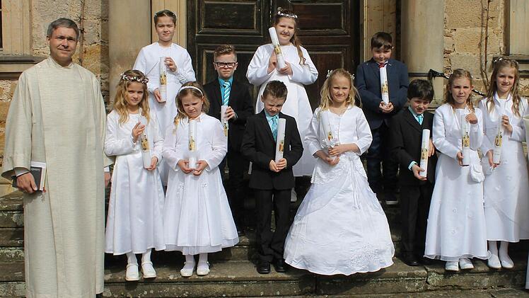 Burgpreppach &mdash; In Burgpreppach feierten diese Kommunionkinder ihre Erstkommunion mit Pfarrvikar Stefan Beetz (rechts) und Pastoralreferent Norbert Zettelmeier (links). Foto: Janina Reuter