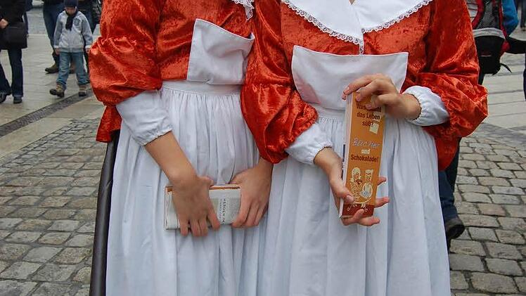 Schätze & Plätze? Bücher & Schokolade! Auf eine Kooperation zweier eigentlich artfremder Geschäfte machten zwei historische Schokoladenmädchen aufmerksam.