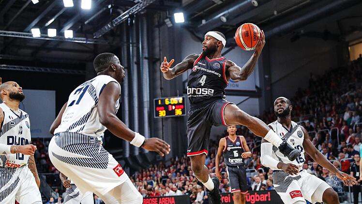 Tyrese Rice war im Hinspiel mit 20 Punkten bester Korbschütze der Bamberger. Hier versperrt Abdoulaye Loum (l.) dem Aufbauspieler den Weg zum Korb; rechts Obi Emegano  Foto: Daniel Löb