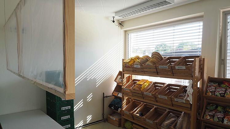 Der Tröpfchen- und Aerosolschutz in den Verkaufsräumen der Coburger Tafel kann hochgehängt werden. Das erleichtert den ehrenamtlichen Mitarbeitern das Sortieren der Lebensmittel. Während der Ausgabezeiten hängen die mit Folien bespannten Holzrahmen knapp über den Tischen. Foto: Christoph Winter