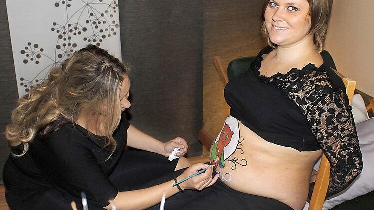Alexandra Lamm bei der Arbeit in ihrem kleinen Atelier in Unterschleichach. Etwa eineinhalb Stunden dauert die Bemalung eines Babybauchs. Nadine hat sich eine Eule als Motiv ausgesucht.  Foto: Katja Müller