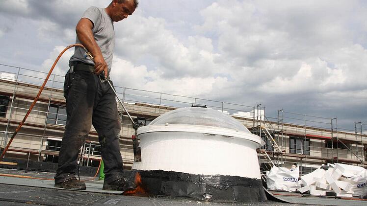 Arbeiter verschweisen die Bahnen auf dem Flachdach. Foto: Ralf Ruppert