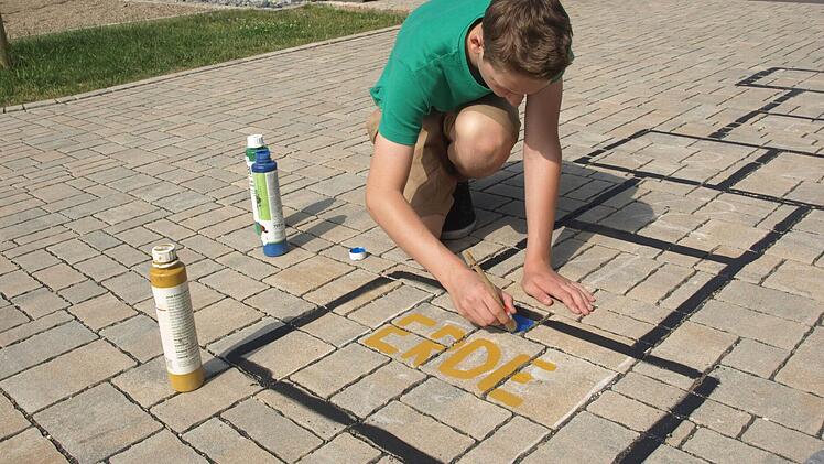 Marco Karch malt im Schulhof ein Spiel auf.