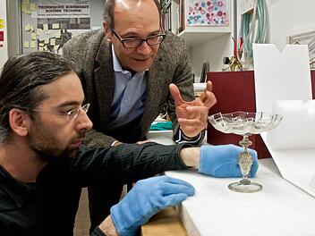 Millimeterarbeit: Restaurator Heiner Grieb (links) und Kurator Sven Hauschke begutachten die Verpackung für venezianische Gläser aus den Beständen der Coburger Kunstsammlungen. Sieben der wertvollen Objekte sind als Leihgaben auf dem Weg nach Paris, darunter auch dieses Exponat aus der zweiten Hälfte des 16. Jahrhunderts.Fotos: Jochen Berger