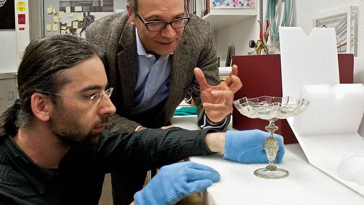 Millimeterarbeit: Restaurator Heiner Grieb (links) und Kurator Sven Hauschke begutachten die Verpackung für venezianische Gläser aus den Beständen der Coburger Kunstsammlungen. Sieben der wertvollen Objekte sind als Leihgaben auf dem Weg nach Paris, darunter auch dieses Exponat aus der zweiten Hälfte des 16. Jahrhunderts.Fotos: Jochen Berger