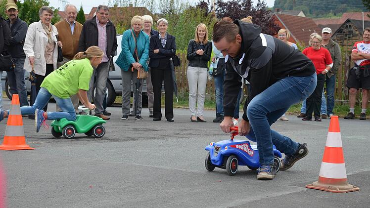 Auf den kleinen Bobbycars hatten die Ministranten am Ende gegen die Vereinsvorstände die Nase vorn. Allerdings nur knapp. Die Gäste des Pfarrfestes konnten einen Tipp abgeben, wer gewinnen wird. Foto: Jana Keul