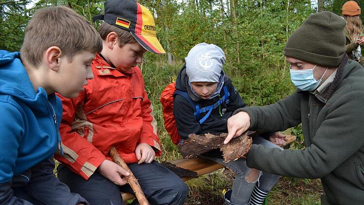 Förster Antoine Klaus zeigt anhand von Baumrinde, wie sich der Borkenkäfer ausbreitet. Foto: Gabi Bertram
