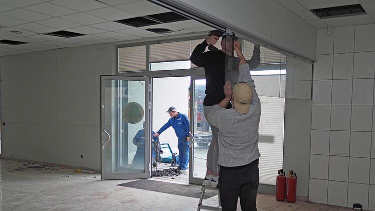 Hier wird eine Glasverkleidung demontiert, während vor der Tür ein Stahlvordach abgebaut wird.