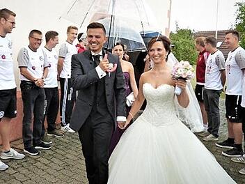 Konstantin Heinrich und seine Ehefrau Olga durchschritten nach ihrer kirchlichen Trauung ein Spalier der Sprtkameraden des FC Neuenmarkt. Foto: Werner Reißaus