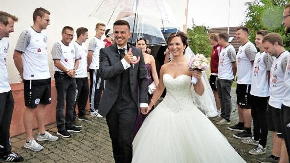 Konstantin Heinrich und seine Ehefrau Olga durchschritten nach ihrer kirchlichen Trauung ein Spalier der Sprtkameraden des FC Neuenmarkt. Foto: Werner Reißaus