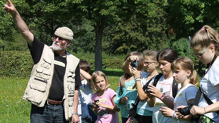 Adrian Price erklärt den Kindern genau, was auf dem Foto abgelichtet sein soll und wie die Lichtverhältnisse sind. Foto: Janina Reuter