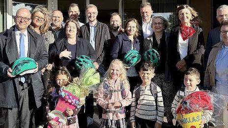 Unser Bild zeigt Oberbürgermeister Dirk Vogel mit einigen Abc-Schützen und ihren Lehrerinnen sowie einem Teil der insgesamt 15 Sponsoren bei der Übergabe der Fahrradhelme an der Henneberg-Grundschule in Garitz.