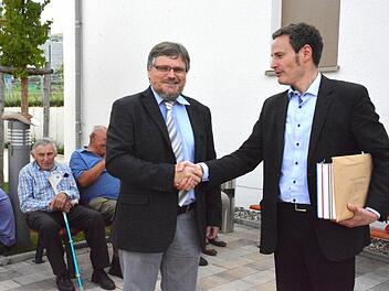 Grabungsleiter Bernhard Häck vom Bayerischen Landesamt für Denkmalpflege (links) überreichte an den Organisator der Brunnengrabung, Pfarrer Peter Bauer (rechts) die Grabungsunterlagen sowie einen Buchband von bayerischen Grabungsobjekten. Foto: Schmidt