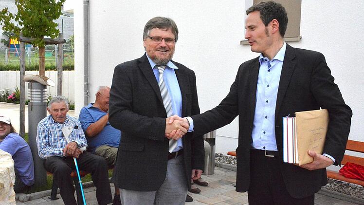 Grabungsleiter Bernhard Häck vom Bayerischen Landesamt für Denkmalpflege (links) überreichte an den Organisator der Brunnengrabung, Pfarrer Peter Bauer (rechts) die Grabungsunterlagen sowie einen Buchband von bayerischen Grabungsobjekten. Foto: Schmidt