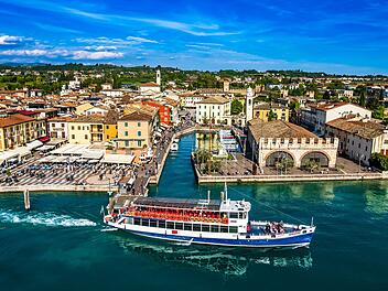 Altstadt und Hafen von Lazise: Lazise am Gardasee ist ein beliebter, malerischer Ort am südöstlichen Gardasee, der eine Mischung aus Geschichte, Kultur und Entspannung bietet. Die historische, autofreie Altstadt mit ihren alten Stadtmauern lädt zum Bummeln, Shopping und Genießen in zahlreichen Cafés und Restaurants ein. Der Ort ist ideal für Wassersport, Badeurlaube und Erholung an den Stränden oder in der Therme. Zudem ist Lazise ein guter Ausgangspunkt für Ausflüge und liegt in der Nähe von Freizeitparks wie Gardaland.