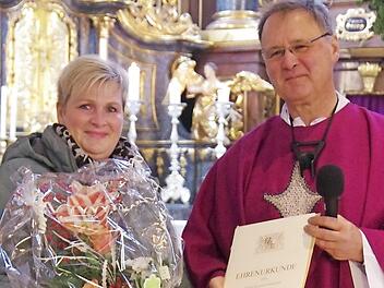 Erzieherin Bettina Münchenbach erhielt für ihre 25-jährige Tätigkeit in der Kindertagesstätte St. Anna von Pfarrer Georg Birkel eine Urkunde und einen Blumenstrauß überreicht.  Foto: Thomas Hümmer