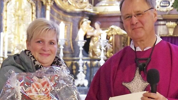 Erzieherin Bettina Münchenbach erhielt für ihre 25-jährige Tätigkeit in der Kindertagesstätte St. Anna von Pfarrer Georg Birkel eine Urkunde und einen Blumenstrauß überreicht.  Foto: Thomas Hümmer