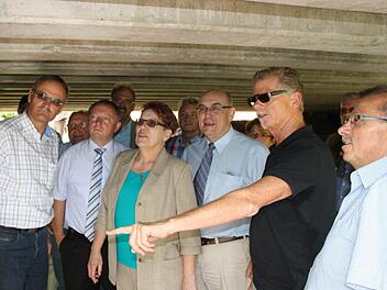 Mitglieder des Wirtschafts- und Umweltausschusses begutachten die Schäden an der Brücke über die Bahnschiene in Hammelburg. Foto: Ralf Ruppert