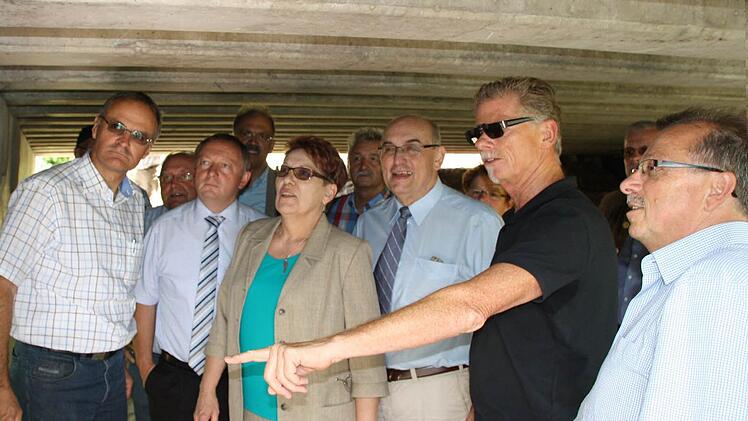 Mitglieder des Wirtschafts- und Umweltausschusses begutachten die Schäden an der Brücke über die Bahnschiene in Hammelburg. Foto: Ralf Ruppert