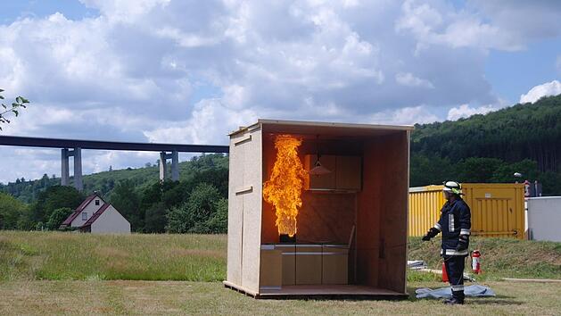 Kommandant Tobias Leitsch demonstrierte, was passiert, wenn man auch nur zu einem Glas Wasser greift und den Inhalt &uuml;ber den &Ouml;lbrand sch&uuml;ttet: Das Wasser verdampft schlagartig und verursacht eine Stichflamme unddann kann die ganze K&uuml;che brennen.  Foto: Stephanie Elm