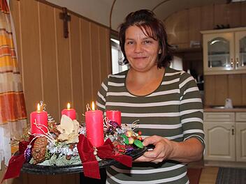 Dunja Renz zeigt stolz den von ihrer Tochter selbst gemachten Adventskranz im Küchen-Wagen. Unter dem Kreuz an der Wand wird am Tag vor Heiligabend der Christbaum aufgestellt. Fürs Schmücken ist Ehemann Alois Renz zuständig. Foto: Popp