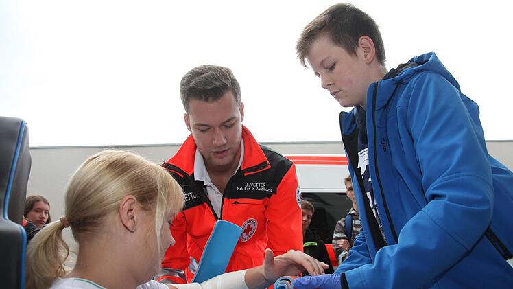 Julian Vetter (Mitte), Auszubildender zum Notfallsanit&auml;ter beim BRK, zeigt mithilfe von Jenny Ploner (links), Praxisanleiterin an den Ha&szlig;berg-Kliniken, die Ruhigstellung einer Armfraktur.Michael Will/BRK