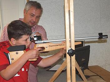 Der elfjährige Philipp Gunzelmann schießt unter Anleitung des Jugendschützenmeisters Jürgen Erlmann mit dem Lichtpunktgewehr auf die elektronische Scheibe. An einem Monitor sieht man die Ergebnisse. Foto: Alfred Thieret