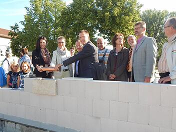 Die zukünftige Krippenleiterin Sabrina Lang, Zweite Bürgermeisterin Jutta Köhler, Architekt Helmut Popp und Bürgermeister Karsten Fischkal (am Behälter v. l.) legten die traditionelle Zeitkapsel gemeinsam in das Mauerwerk der neuen Adelsdorfer Kinderkrippe. Foto: Mona Lisa Eigenfeld