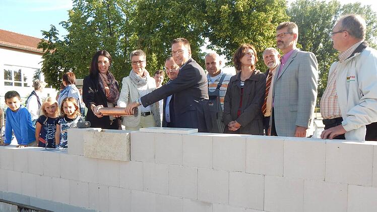 Die zukünftige Krippenleiterin Sabrina Lang, Zweite Bürgermeisterin Jutta Köhler, Architekt Helmut Popp und Bürgermeister Karsten Fischkal (am Behälter v. l.) legten die traditionelle Zeitkapsel gemeinsam in das Mauerwerk der neuen Adelsdorfer Kinderkrippe. Foto: Mona Lisa Eigenfeld