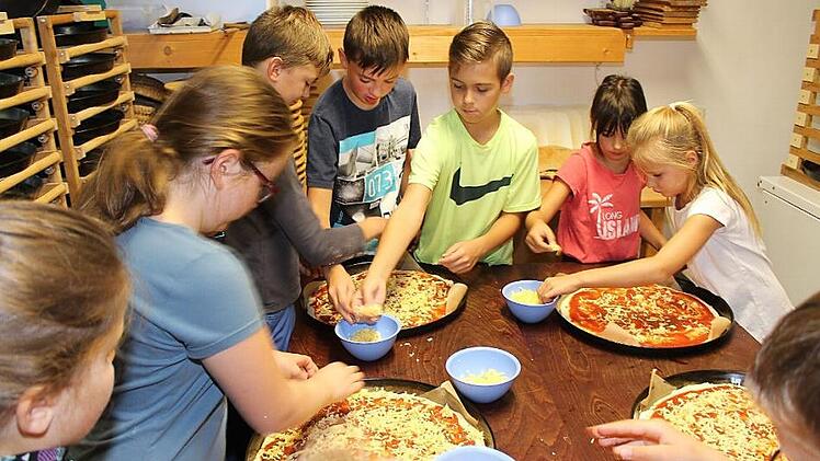 Endlich werden die Pizzen mit Schinken, Salami, Paprika und natürlich Käse belegt und dürfen in den Holzbackofen wandern.  Foto: Roland Dietz