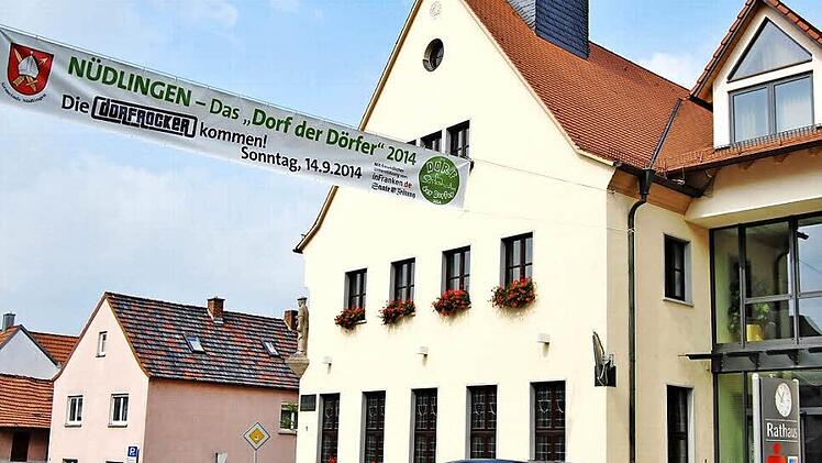 Zu Recht stolz auf den Titel: Das Werbebanner über der Hauptstraße wirbt neben dem Rathaus für Nüdlingen als "Dorf der Dörfer". Foto: Sigismund von Dobschütz