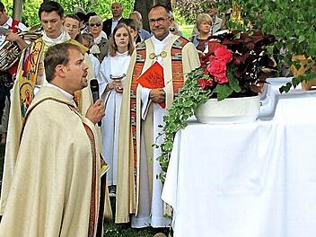 Die Prozession macht Halt am zweiten Altar im Hofgarten. Kaplan Johannes Saffer hält eine kurze Andacht und erteilt den eucharistischen Segen. Die Geistlichen hinten sind Pfarrer Tomasz Dzikowski und Dekan Roland Huth.  Foto: Martin Koch