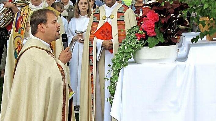 Die Prozession macht Halt am zweiten Altar im Hofgarten. Kaplan Johannes Saffer hält eine kurze Andacht und erteilt den eucharistischen Segen. Die Geistlichen hinten sind Pfarrer Tomasz Dzikowski und Dekan Roland Huth.  Foto: Martin Koch