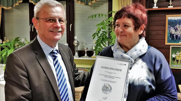 Bürgermeister Gotthard Schlereth überreicht die Dankurkunde des Landratsamtes an Erika Happ vom Team der katholischen Bücherei.  Foto: Sigismund von Dobschütz