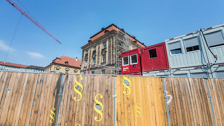 Durchblick auf die Justiz-Baustelle: Gucklöcher in Paragrafenzeichen im Bauzaun.