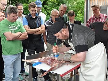 Aufmerksam verfolgen die Gäste des Wildzerlege- und Grillkurses, wie Martin Burmann mit dem Messer den Wildgenuss vorbereitet.  : Baysf