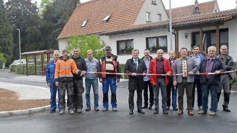 Unter den Augen von Vertretern der beteiligten Firmen und Gemeindevertretern durchschneidet Bürgermeister Rainer Detsch (6. v. l.) das Absperrband und gibt die Straße wieder für den Verkehr frei. Foto: K.- H. Hofmann