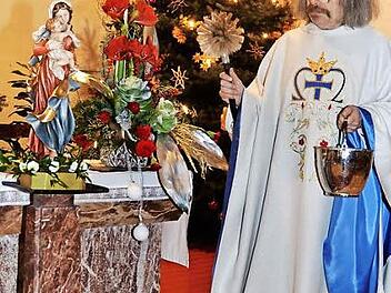 Pater Helmut Haagen segnet die Madonna- Statue mit Jesuskind, die für einen Fronleichnamsaltar eingesetzt wird. Foto: K.- H. Hofmann