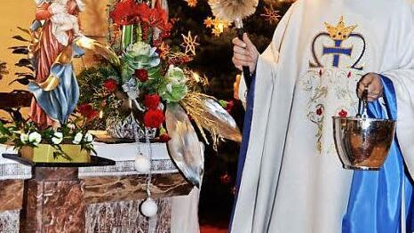 Pater Helmut Haagen segnet die Madonna- Statue mit Jesuskind, die für einen Fronleichnamsaltar eingesetzt wird. Foto: K.- H. Hofmann