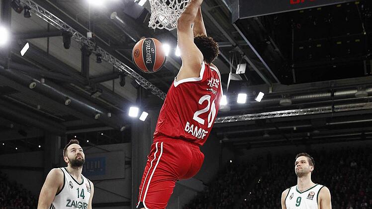 Elias Harris stopft den Ball in den Ring, Ian Vougioukas (l.) und Mantas Kalnietis (r.) von Zalgiris Kaunas schauen konsterniert zu. Fotos: Daniel Löb