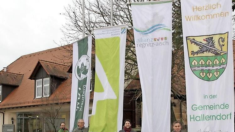 Der Geschäftsführer der Waldbesitzervereinigung (WBV) "Kreuzberg", Matthias Koch, Revierförster Matthias Jessen, Allianzmanager Niklas Rhein und Bürgermeister Torsten Gunselmann befestigten die Fahnen an den Masten. Foto: Mathias Erlwein