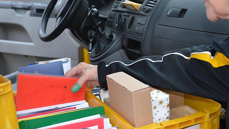 Auf dem Beifahrersitz von Christine Apels Dienstauto stehen kleine Kisten mit Umschlägen und Werbefoldern, die sie mit der Post verteilt.