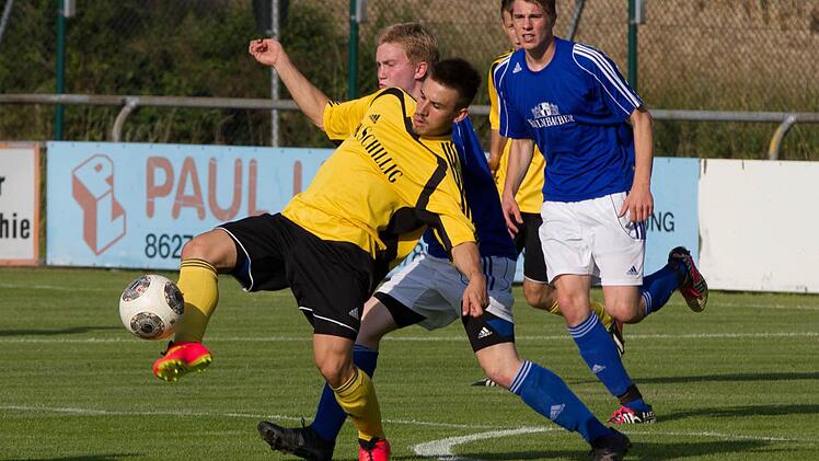 Der Frohnlacher Torschütze Lukas Werner (gelb) wird von Daniel Weiner angegriffen und spielt der Ball mit der Fußspitze weiter.