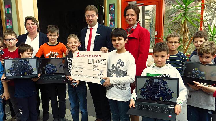 Bei der Feier in der Schule präsentieren die Schüler die neuen Rechner zusammen mit (von links)  Rektorin Silke Schür, Jürgen Klaus und Nicole Mainusch.  Die Calliope-Scheiben sind auf den Laptops abgebildet. Foto: Dagmar Niemann
