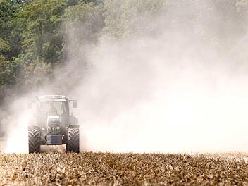 Ein Traktor pflügt ein trockenes Feld und zieht eine große Staubwolke hinter sich her. Ernteausfälle wie durch die derzeitige Trockenheit verstärken die strukturellen Probleme der Landwirte noch. Foto: Gollnow, dpa