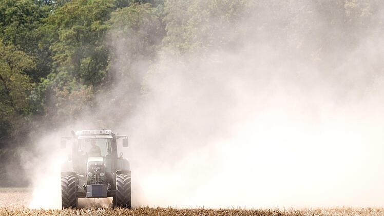 Ein Traktor pflügt ein trockenes Feld und zieht eine große Staubwolke hinter sich her. Ernteausfälle wie durch die derzeitige Trockenheit verstärken die strukturellen Probleme der Landwirte noch. Foto: Gollnow, dpa