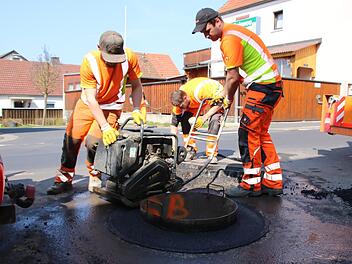Bauleiter Stefan Etz und seine Kollegen sind ein eingespieltes Team: Während zwei Arbeiter vorne das Mischgut  für einen Kanaldeckel rütteln, wird hinten  die nächste Grube vorbereitet. Foto: Ralf Ruppert